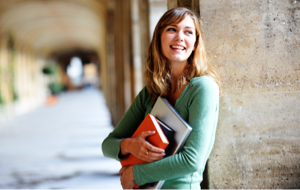 Female students holding textbooks and walking on campus