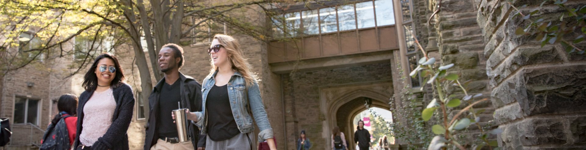 Three students walk on the pathway behind University Hall on McMaster campus